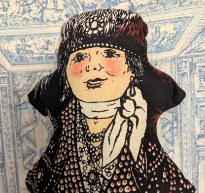 Printed pearly queen stuffed doll shown against a decorative toile background.